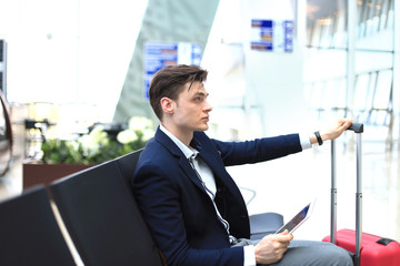 businessman checking time and using tablet at airport.