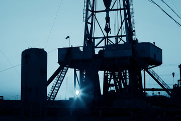 The oil derrick, under the setting sun