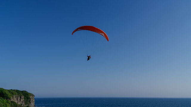 A man flies on paraplane above the sea