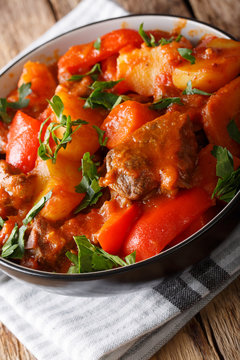 Slow cooked beef with potatoes, tomatoes, pepper, carrots and onions close up in a bowl. vertical