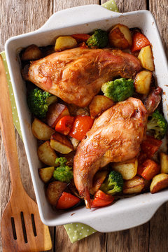 rabbit baked with vegetables in mustard sauce close-up in baking dish. Vertical top view