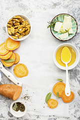 Ingredients for a healthy and comfortable diet: slices of fresh raw sweet potato, honey, walnuts, rosemary cheese, sage, salt on a light background using a sheet of parchment. Top View. Copy space