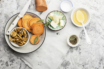 Ingredients for a healthy and comfortable diet: slices of fresh raw sweet potato, honey, walnuts, rosemary cheese, sage, salt on a light background using a sheet of parchment. Top View. Copy space