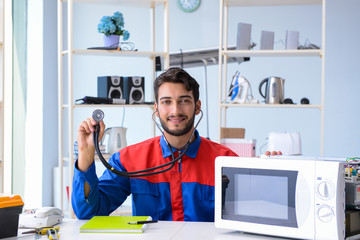 Young repairman fixing and repairing microwave oven