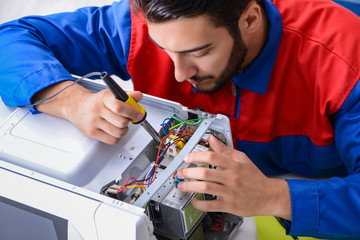 Young repairman fixing and repairing microwave oven