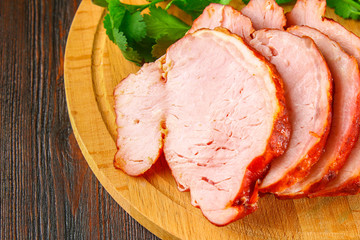 Sliced Roast Pork Loin on a brown wooden table with cilantro.