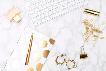 Keyboard c of office items of gold color and cosmetics on the desktop of the house. Flat lay