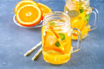 Orange detox water in mason jars on a gray concrete background. Healthy food, drinks.
