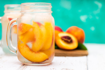 Homemade iced lemonade with ripe peaches. Fresh peach ice tea in a mason jar.