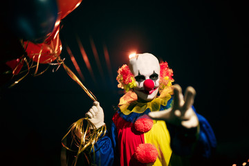 Picture of smiling clown with balls in hands at night