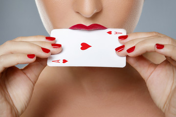 Woman with red lips is holding ace card in her hands