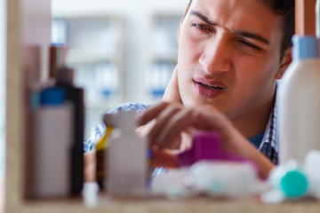 Sick ill man looking for medicines at farmacy shelf