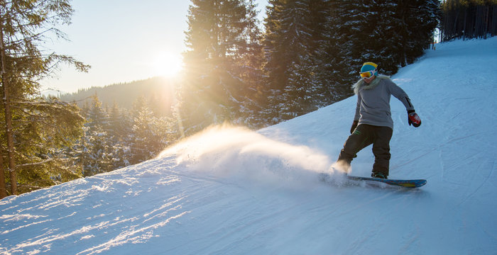 Full length shot of a female snowboarder skiing on snowy slope on the dawn in the mountain ski resort copyspace scenery nature evening powder freeride snowboarding copyspace