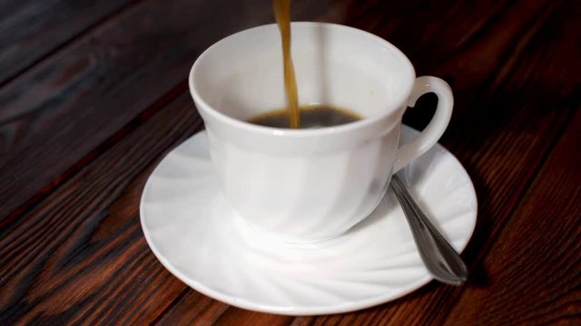 A cup of hot coffee stands on a wooden table 
