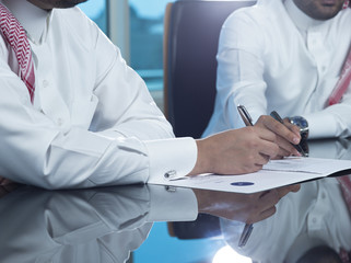 Two Saudi businessmen hands signing a document