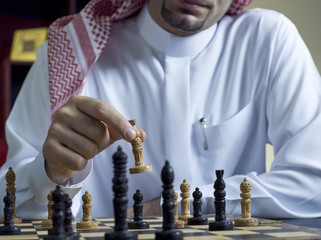 An Arab man playing chess at his desk