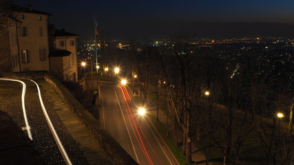 Fototapeta na wymiar Bergamo, Italy. The old city. Landscape on the street long the ancient walls during the evening with trails of headlights