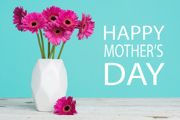 Happy Mother's Day Pastel Candy Blue Coloured Background with Dark pink gerberas in a vase.
