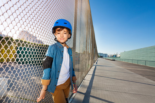 Happy boy in helmet standing at outdoor rollerdrom