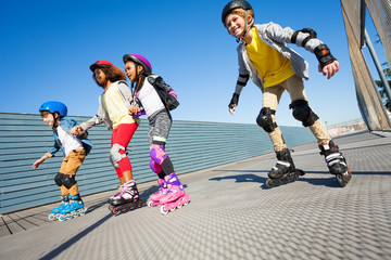 Fototapeta na wymiar Happy kids rollerblading on the road at sunny day
