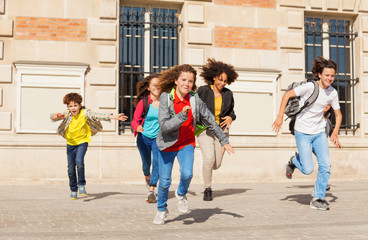 Cute pupils running  from school building