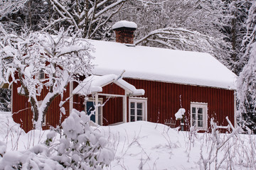 red wooden house in a snowy and cold varmland sweden