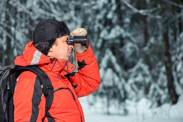 lonely lost tourist man in winter forest with binoculars looking to the right