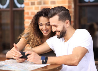 Happy loving  couple using a smartphone sitting in terrace