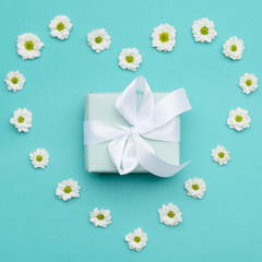 Happy Mother's Day, Women's Day, Valentine's Day or Birthday Background. Pastel Blue Candy Colour  flat lay minimal concept with beautifully wrapped present and daisies in a heart shape.