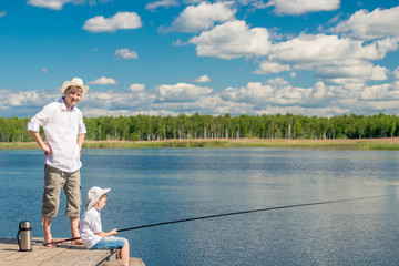 father and son on a wooden pier on a sunny day fishing