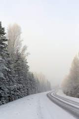 Winding and wintry road in Finland. Curves with snow covered asphalt road. Empty highway for traveling.