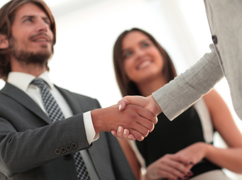 Businesspeople  shaking hands against room with large window loo
