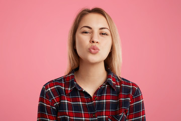 Horizontal shot of beautiful female with rounded lips, going to kiss boyfriend, expresses great...