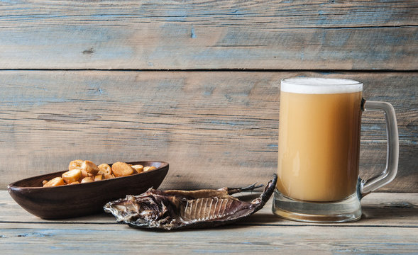 A glass of light beer with dried fish close-up on a black background