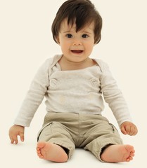 Funny baby sitting on the floor, isolated over white