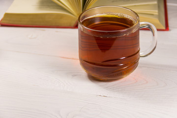 Cup of tea and book on white wooden table