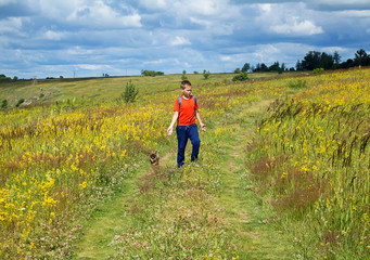 Thoughtful little boy the traveler stands on a beautiful summer meadow, against a blue sky