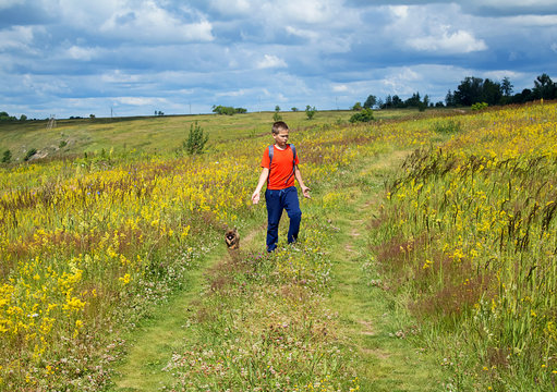 Thoughtful little boy the traveler stands on a beautiful summer meadow, against a blue sky