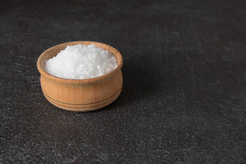 sea salt in a wooden bowl on a dark background