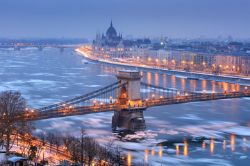 Naklejka na ściany i meble Szechenyi chain bridge and Pest riverfront with Parliament outline in winter night, Budapest