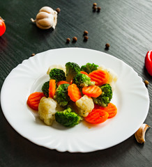 Mixed vegetables. cauliflower, broccoli and carrots in plate on a dark wooden background