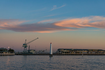 Fototapeta premium Wharf with hoisting crane and lighthouse at dusk
