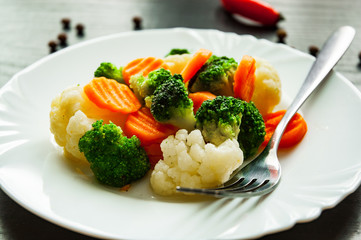 Mixed vegetables. cauliflower, broccoli and carrots in plate on a dark wooden background