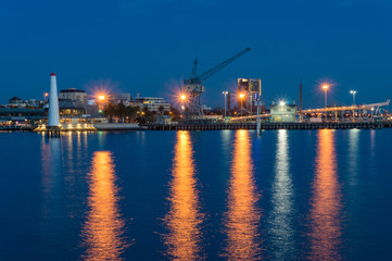 Wharf with crane and lighthouse at dusk