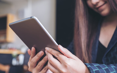 A woman's hands holding and using tablet pc with blur background in cafe