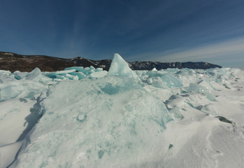 dawn in the blue hummocks of ice lake baikal, in a snowy field in winter on a journey