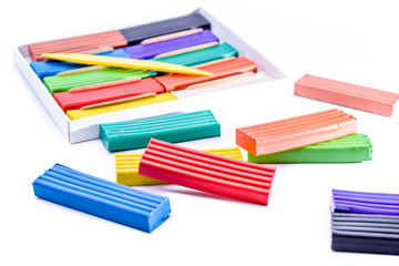 colorful plasticine in a box with a plastic knife on white background