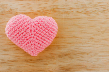Obraz premium Pink heart knit with yarn on wooden floor.