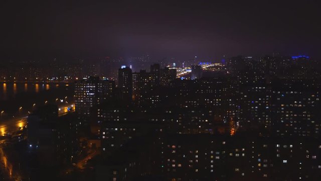 shooting night city. The lights are burning in the windows of apartment buildings. On the asphalt reflections glare from the passing cars. light is splashing in the water. lake or river. night Kiev
