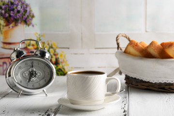 Start up concept.Coffe cup,alarm clock and toast in the basket. Morning coffee day start.